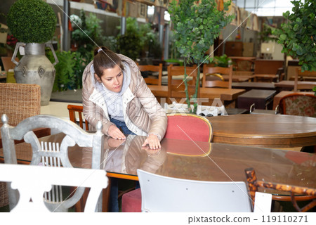 Woman chooses table in furniture store 119110271