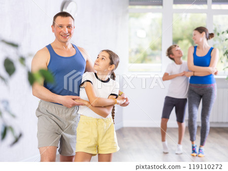 Father practicing dance in pair with her tween son during family dance class 119110272