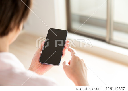 A middle-aged woman looking at her smartphone during an apartment viewing 119110857