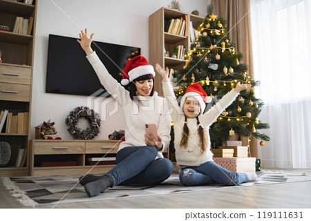 Mother and daughter celebrating Christmas together on floor Mother and daughter celebrating Christmas together on floor 119111631