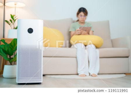 Air Purifier with woman relax and use tablet on sofa. Purification system for filter and cleaning dust PM2.5 HEPA and virus in home. Allergy, Pure air, health, Wellness lifestyle and Air Pollution 119111991