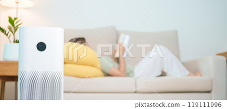 Air Purifier with woman read and relax on sofa. Purification system for filter and cleaning dust PM2.5 HEPA and virus in home. Allergy, Pure air, health lifestyle, Wellness life and Air Pollution 119111996