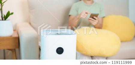 Air Purifier with woman relax and use smartphone on sofa. Purification system for filter and cleaning dust PM2.5 HEPA and virus in home. Allergy, Pure air, health, Wellness lifestyle and Air Pollution Air Purifier with woman relax and use smartphone on sofa. Purification system for filter and cleaning dust PM2.5 HEPA and virus in home. Allergy, Pure air, health, Wellness lifestyle and Air Pollution 119111999