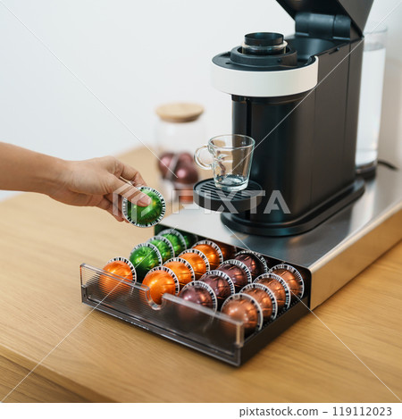 hand making Espresso Coffee by Coffee Maker Machine with Capsule of roasted coffee bean on wood table bar. Daily beverage drink at Home, Apartment and Office concept hand making Espresso Coffee by Coffee Maker Machine with Capsule of roasted coffee bean on wood table bar. Daily beverage drink at Home, Apartment and Office concept 119112023