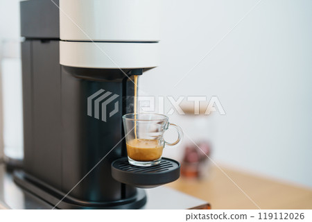 Espresso cup with steam and froth during Coffee making Coffee by Coffee Maker Machine on wood table bar. Cafe shop, Daily beverage drink at Home, Apartment and Office concept Espresso cup with steam and froth during Coffee making Coffee by Coffee Maker Machine on wood table bar. Cafe shop, Daily beverage drink at Home, Apartment and Office concept 119112026