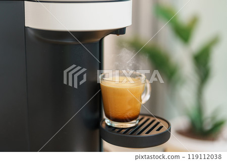 Espresso cup with steam and froth during Coffee making Coffee by Coffee Maker Machine on wood table bar. Cafe shop, Daily beverage drink at Home, Apartment and Office concept Espresso cup with steam and froth during Coffee making Coffee by Coffee Maker Machine on wood table bar. Cafe shop, Daily beverage drink at Home, Apartment and Office concept 119112038