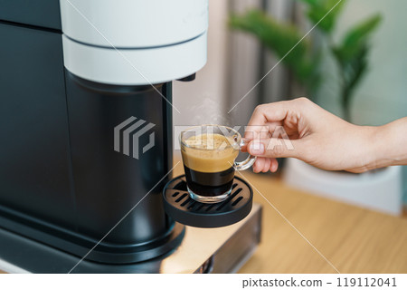 Espresso cup with steam and froth during Coffee making Coffee by Coffee Maker Machine on wood table bar. Cafe shop, Daily beverage drink at Home, Apartment and Office concept 119112041