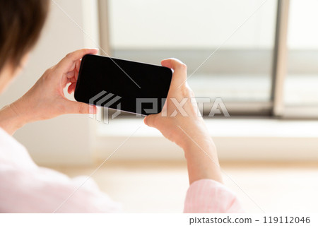 中年婦女在看公寓時看著智慧型手機 中年婦女在看公寓時看著智慧型手機 119112046