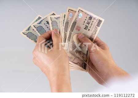 Detailed shot of Yen banknotes being counted: Illustrates financial decision-making and monetary interactions in Japanese economy 119112272