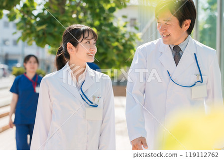 身穿白大褂的男女醫生、醫師、醫務工作者、研究人員和科學家在醫院外行走 119112762