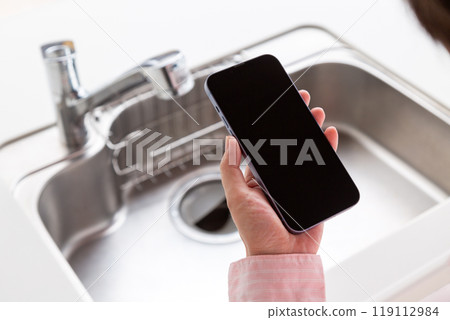 公寓廚房裡拿著智慧型手機的中年婦女 119112984