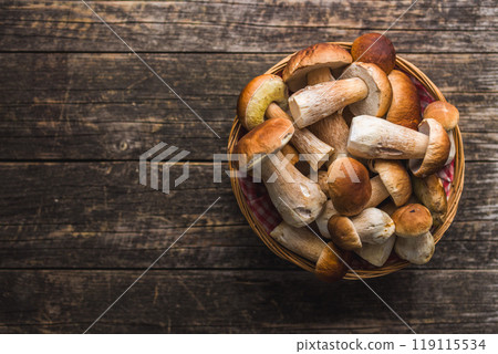 Fresh boletus mushrooms in basket on wooden table. Top view. 119115534