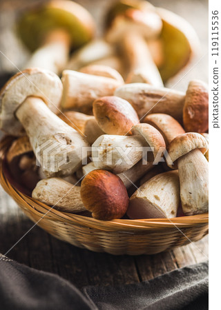 Fresh boletus mushrooms in basket on wooden table. 119115536