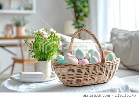 in a bright living room on a table with a white tablecloth, a wicker basket with Easter eggs in pastel colors 119116170