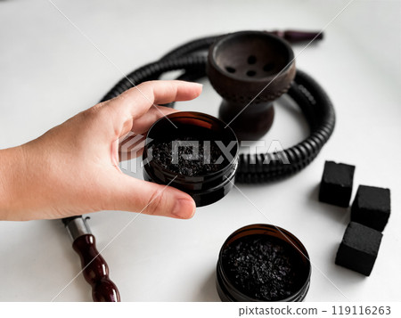 Hand holding hookah tobacco with shisha accessories and charcoal on white background 119116263