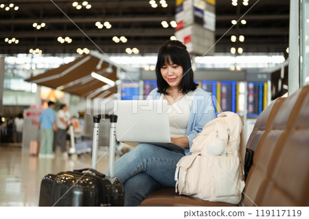 Pretty young woman using laptop in airport terminal waiting for her flight Pretty young woman using laptop in airport terminal waiting for her flight 119117119