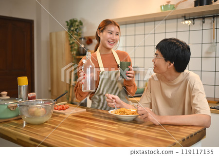 Happy young couple chatting and enjoying their lunch in domestic kitchen 119117135