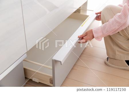 中年婦女看著廚房櫥櫃儲藏室 119117230