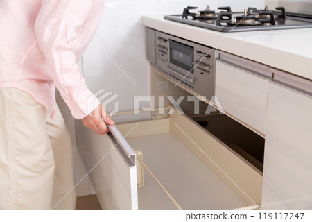 Middle-aged woman looking at kitchen cabinet storage Middle-aged woman looking at kitchen cabinet storage 119117247