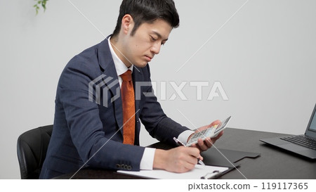 一位商人計算存摺金額的手 一位商人計算存摺金額的手 119117365