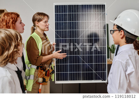 Caucasian female engineer telling about types of solar energy panels during career guidance class at school, teen students listening to her 119118012