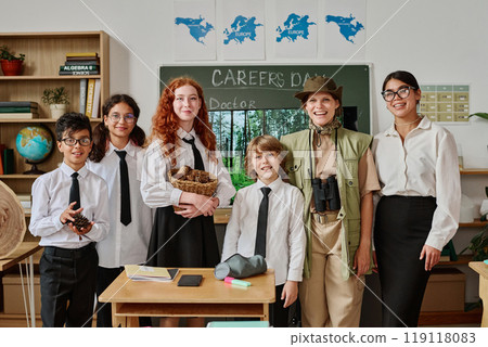 Young female teacher, professional forester and group of teenagers posing for portrait in classroom at school 119118083