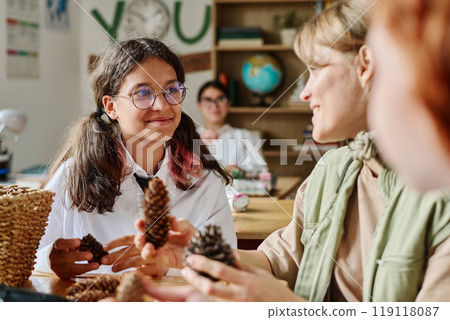 Cheerful teen schoolgirl enjoying stories told by female forester during career guidance class at school 119118087
