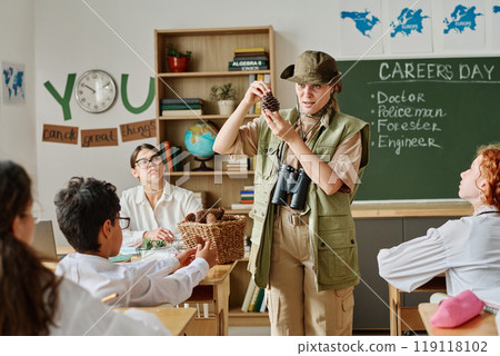 Female forester showing pine cones to group of teen students during career guidance class at school 119118102