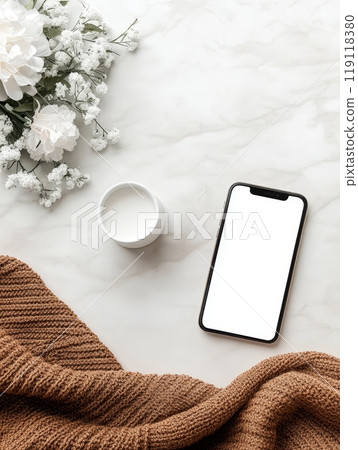 Elegant flat lay of a smartphone, white cup, and delicate flowers on a marble surface with cozy knit fabric, perfect for social media Elegant flat lay of a smartphone, white cup, and delicate flowers on a marble surface with cozy knit fabric, perfect for social media 119118380