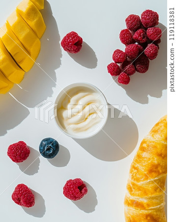 Fresh sliced mango, raspberries, and croissant arranged with creamy yogurt on white background, showcasing a vibrant and healthy breakfast spread Fresh sliced mango, raspberries, and croissant arranged with creamy yogurt on white background, showcasing a vibrant and healthy breakfast spread 119118381