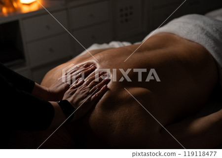Woman masseuse doing professional back massage to man in spa salon. Woman masseuse doing professional back massage to man in spa salon. 119118477