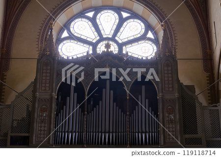 the pipe organ of a church under a rose window full of light the pipe organ of a church under a rose window full of light 119118714