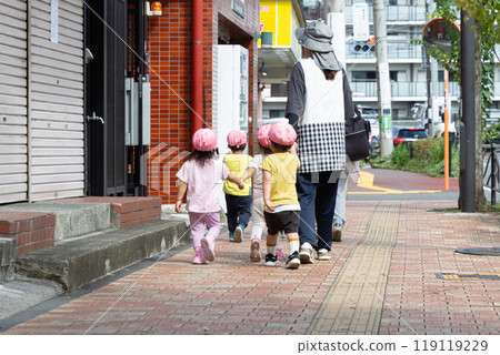 Back view of kindergarten children and teacher walking on the sidewalk 119119229
