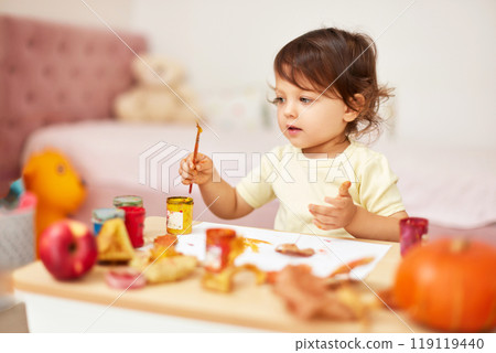 happy little child girl painting autumn leaves. baby girl drawing leaves in yellow and orange paint happy little child girl painting autumn leaves. baby girl drawing leaves in yellow and orange paint 119119440