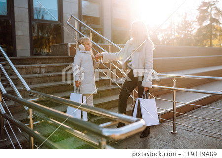 Young mother and little girl with shopping bags after shopping. Spring Style. Consumerism. 119119489