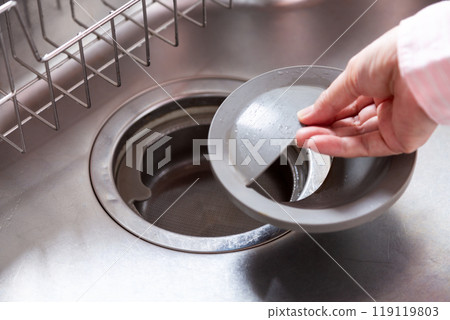 A middle-aged woman looking at the drain of the kitchen counter A middle-aged woman looking at the drain of the kitchen counter 119119803