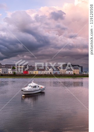 Sunset in Galway City with small boat in the foreground and storm clouds glowing pink and grey hues 119120508