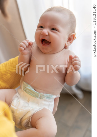 Young mom in bedroom or nursery room interior holding cute newborn little child 119121140