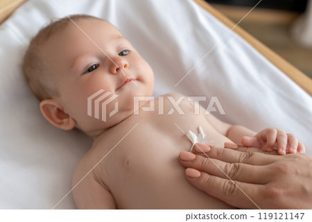 Mother applying lotion to care for her newborn’s skin at home 119121147