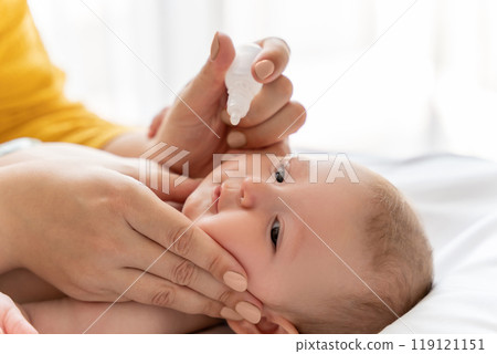 Mother dripping nasal drops for her infant at home Mother dripping nasal drops for her infant at home 119121151