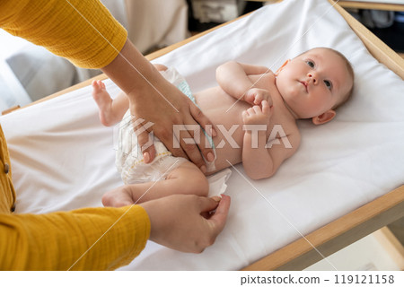 Mother changing her newborn's diaper in the nursery ensuring the baby's hygiene 119121158