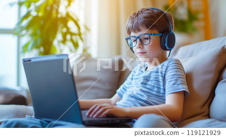 Boy watching video with headphone on laptop computer at home. Boy watching video with headphone on laptop computer at home. 119121929