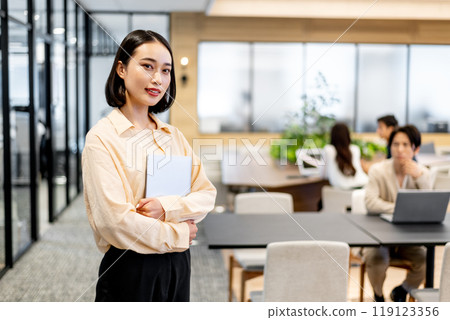 A woman holding a laptop and looking at you 119123356