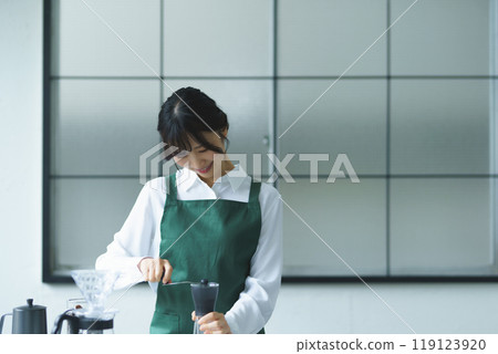 週末早上，一位年輕的女店員正在煮咖啡 119123920