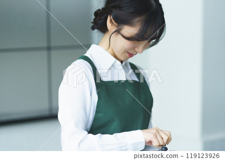 A young female sales clerk brewing coffee on a weekend morning 119123926
