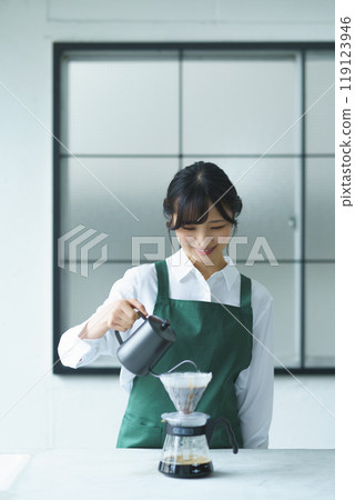 A young female sales clerk brewing coffee on a weekend morning 119123946