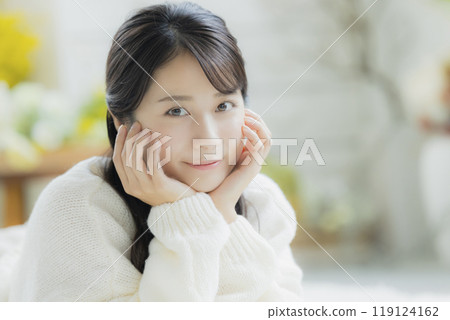 A woman lying down in a white knitted sweater 119124162