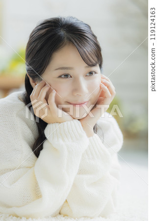 A woman lying down in a white knitted sweater 119124163
