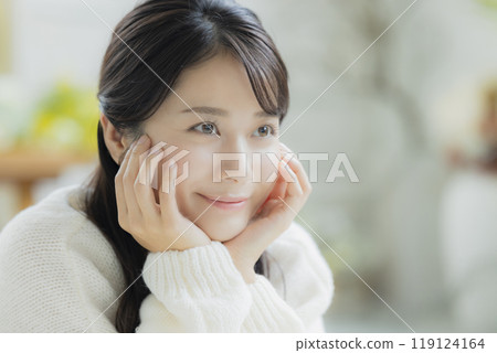 A woman lying down in a white knitted sweater 119124164