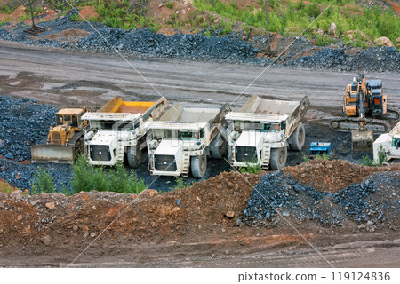 Bulldozer, dump trucks and an excavator at the bottom of the quarry Bulldozer, dump trucks and an excavator at the bottom of the quarry 119124836